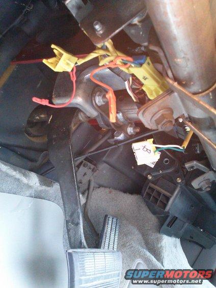 Under dash view showing wiring harnesses, connectors, brake pedal, and accelerator pedal