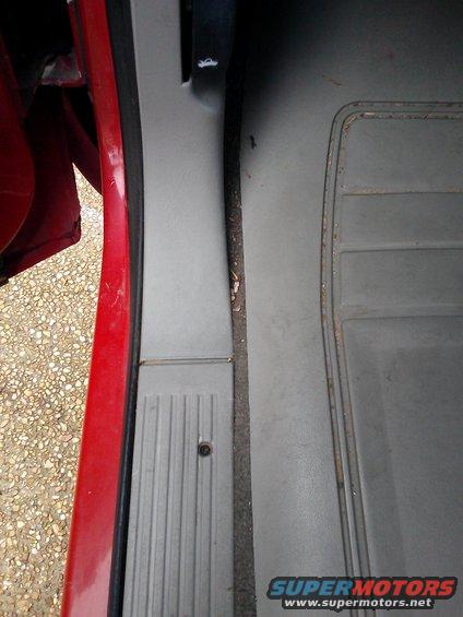 Red door frame and gray interior trim with ribbed plastic sill plate and textured floor mat