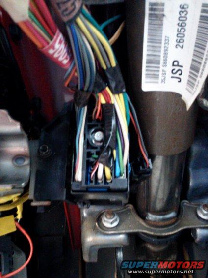 Close-up of a vehicle's interior wiring harness and fuse box with many colored wires