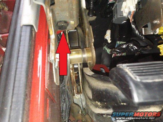 Interior view of vehicle mechanism with red arrow pointing to metal part