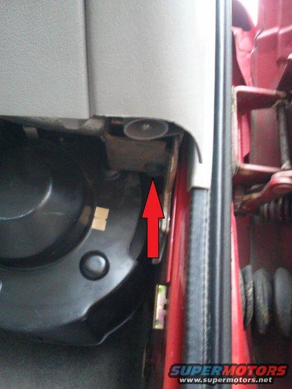 Close-up of interior door jamb with red arrow pointing to a metal bracket