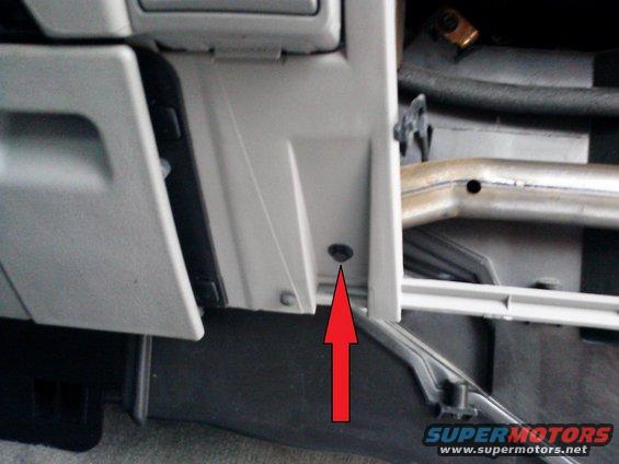 Interior vehicle part with red arrow pointing to screw