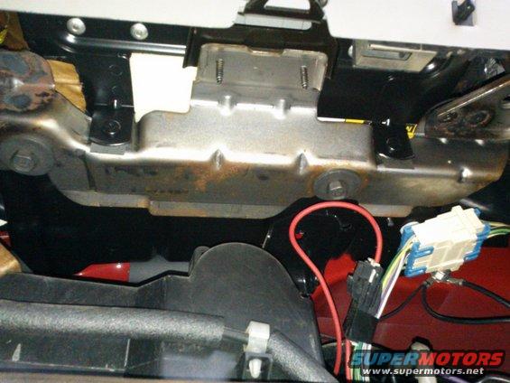 Close-up of wiring harness and metal bracket under a vehicle's dashboard