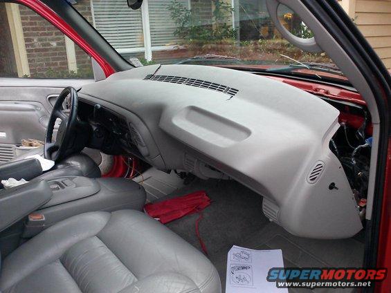 Red truck interior with gray dashboard removed, showing exposed wiring and gray leather seats
