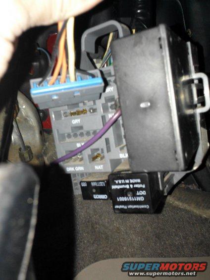 Close-up of vehicle interior wiring harness and fuse box with visible labels like GRY, NAT, and BLK