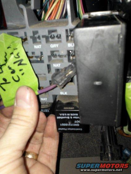 Fuse box with green tape and handwritten notes, purple wire, and black relay