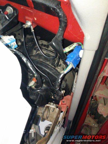 Close-up of vehicle wiring harness with blue connector and black tape