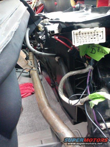 Vehicle interior showing wiring harness and connector block, with green tape labels