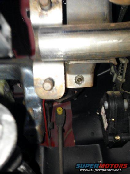 Close-up of a metal mounting bracket with bolts and wires in a vehicle's interior
