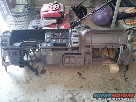 Dashboard assembly with radio and vents removed, sitting on a concrete floor