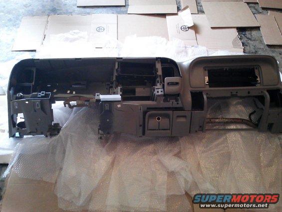 Disassembled vehicle dashboard assembly, gray plastic, with exposed wiring and mounting brackets