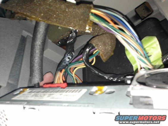 Vehicle interior wiring harness with colorful wires and black tape, connected to a silver component