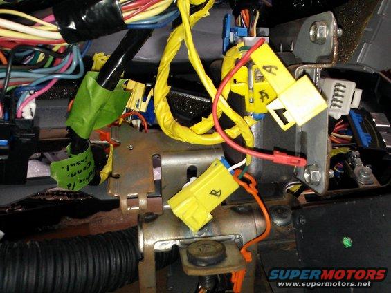 Close-up of yellow and blue connectors and wiring harness under dashboard