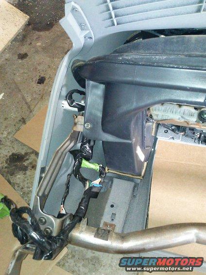 Close-up of vehicle dashboard wiring harness and metal support structure