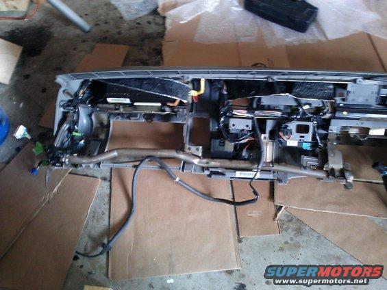 Vehicle dashboard assembly with wiring and metal supports, laid out on cardboard
