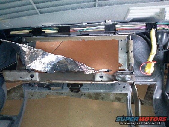 Car interior showing exposed wiring, insulation, and metal bracing under the dashboard