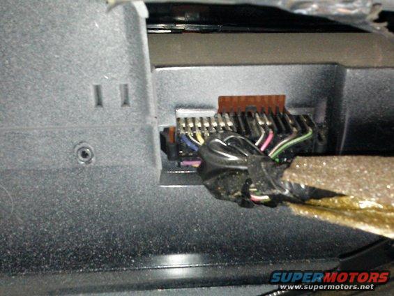 Close-up of a vehicle's interior wiring harness with multiple colored wires connected to a plug