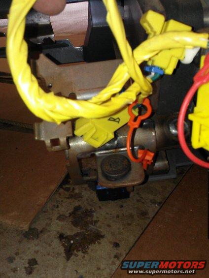 Yellow-wrapped wiring harness and orange safety clip on steering column