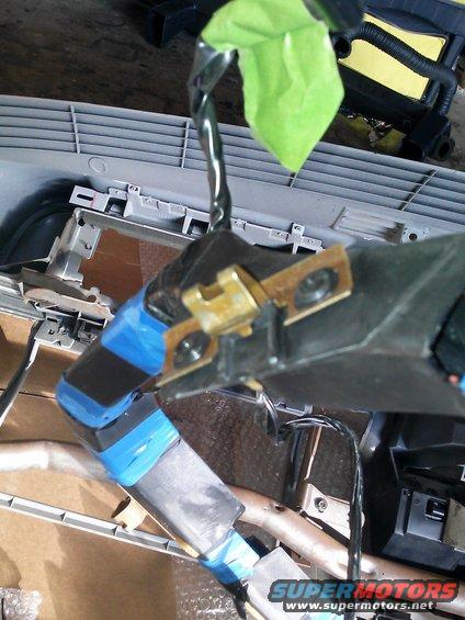 Dashboard wiring harness with blue and black tape, and green tape on a wire, inside a vehicle