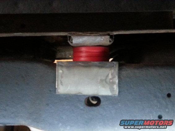 Suspension lift block with red polyurethane spacer between metal brackets
