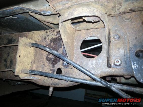 rusted vehicle frame section with brake lines visible
