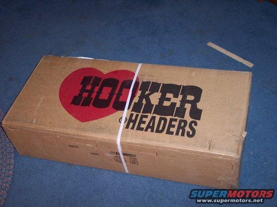 Cardboard box with red heart and black text 'HOOKER HEADERS' logo, secured with white straps