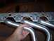 1990 Ford Bronco - Exhaust manifold part shown up close, with a hand holding one of the pipes.