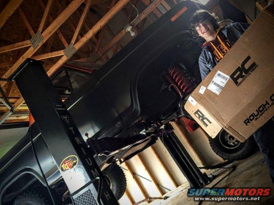 Black Ford Bronco interior with a person holding a Rough Country suspension box