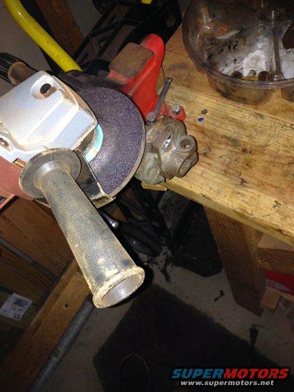 Angle grinder with a grinding wheel held by a red vise on a wooden workbench