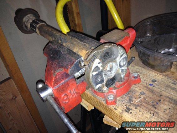 Drive shaft component clamped in a red vise on a workbench
