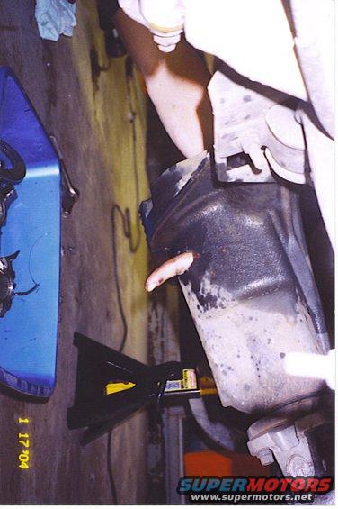 Close-up of a vehicle's differential with a hand reaching towards it, supported by a jack stand. Date stamp reads 1 17 '04