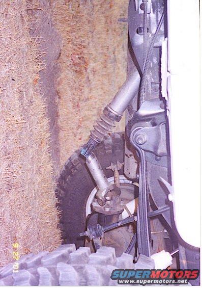1994 Ford Bronco front suspension damage, tire and hay bales visible