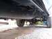 1978 Ford F-250 - The underside of a truck shows its frame, suspension components, and rear axle, with a wheelbarrow in the background.