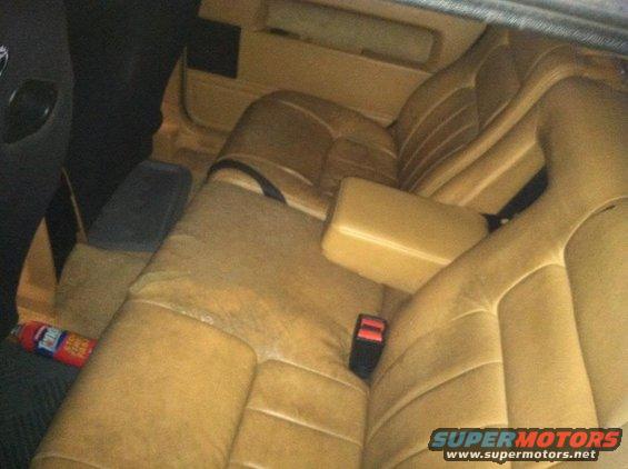 Tan leather rear car seats with a red fire extinguisher on the floor