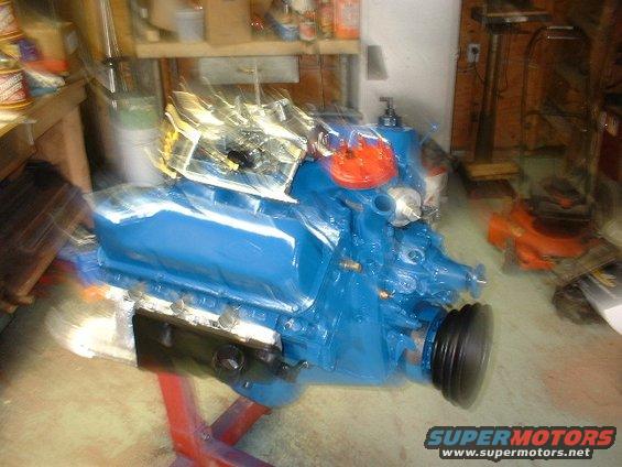 Blue engine block with orange distributor cap on a red engine stand in a workshop