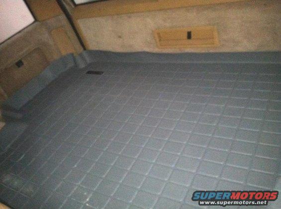 Car interior cargo area with a diamond-patterned rubber mat covering the floor
