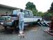 1978 Ford F-250 - Two men work on a 1978 Ford F-250 truck that is raised on jack stands with its hood open.