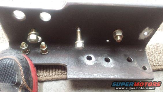 Metal bracket with several bolts and nuts, a shoe is visible on the left