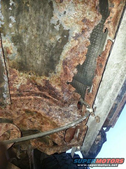 Heavily rusted metal undercarriage with a brake line visible