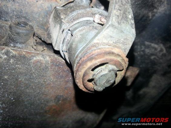 Close-up of a rusted metal bracket and bolt assembly on a vehicle's undercarriage