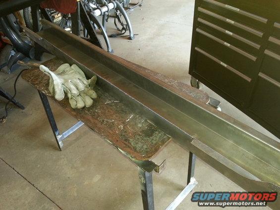 Metal beam on workbench with work gloves and Supermotors logo