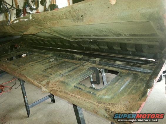 Rusted car floor pan, viewed from above, on sawhorses
