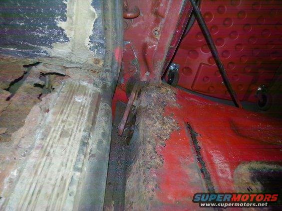 Rusted interior floor pan with red paint and metal supports