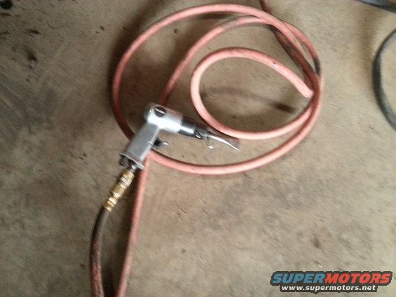 air hammer with orange hose coiled up on concrete floor