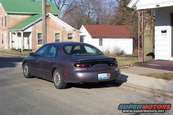1996 Ford Taurus sedan, rear 3/4 view, parked on street. License plate reads T30 5570