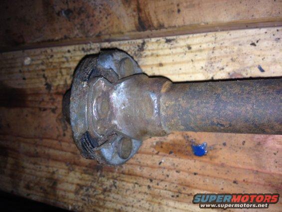 Close-up of a rusty driveshaft U-joint assembly on wooden planks