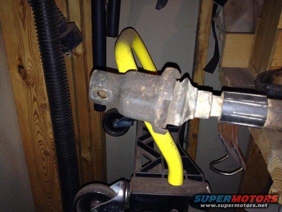 Rusty metal automotive part with yellow support, on a stand with wheels
