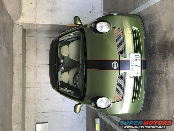 Green 2003 Nissan Micra with black and red racing stripes on the hood