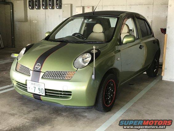Green hatchback with black and red racing stripes on the hood and roof. Has a black roof and black wheels with red trim