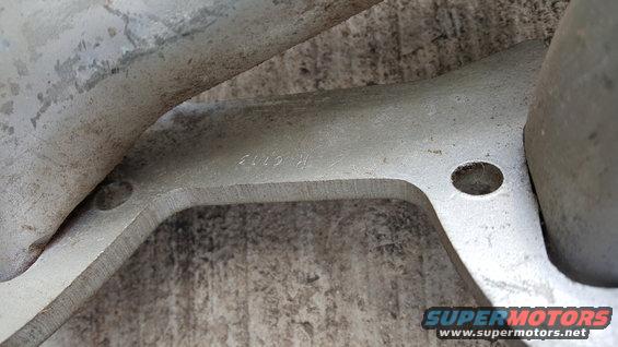 Close-up of a metal casting with the numbers '2112 R' stamped on it